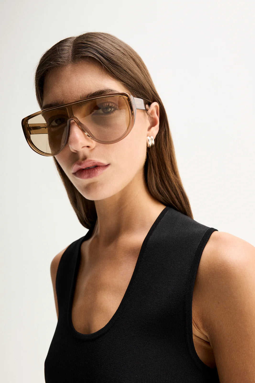 A close-up shows a model wearing the Elka Collective Hayes Knit Top in Black with a narrow scoop neckline and ribbed texture.
