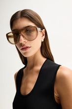 A close-up shows a model wearing the Elka Collective Hayes Knit Top in Black with a narrow scoop neckline and ribbed texture.
