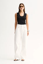A model wears the Elka Collective Hayes Knit Top in Black with white wide-leg trousers in a full-length front view.
