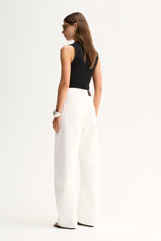 A back view shows the Elka Collective Hayes Knit Top in Black styled with white wide-leg trousers.
