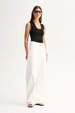 A model wears the Elka Collective Hayes Knit Top in Black with white wide-leg trousers in a full-length front studio view.
