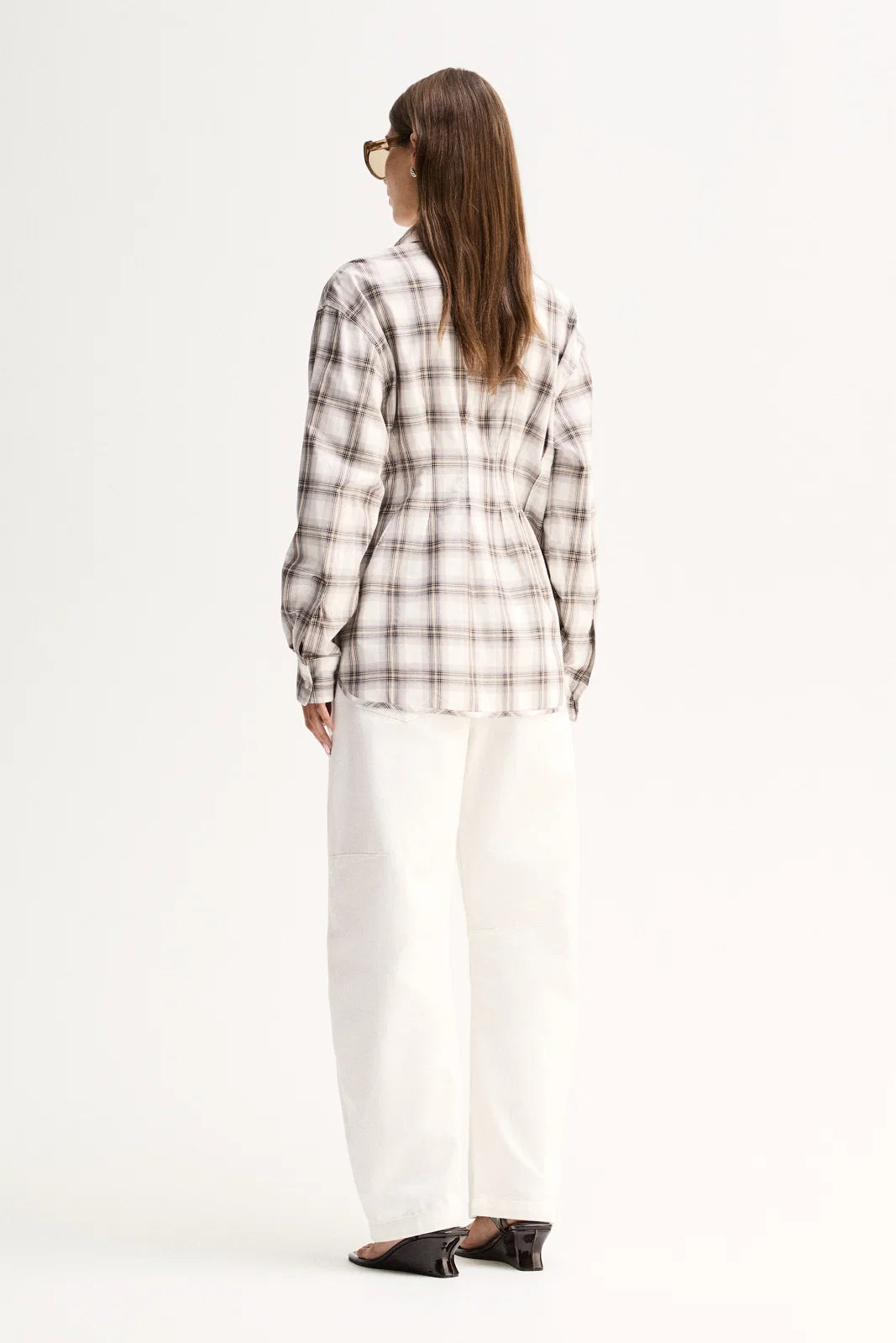 A model wears the White Check shirt in a full-length back view showing its long sleeves and shaped silhouette.