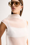 Close-up view of a woman wearing the white sheer mock-neck top with oversized sunglasses, highlighting the layered neckline and sleeveless design.