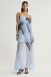 A full-length front view of a pale blue organza maxi dress featuring a square neckline, thin shoulder straps and oversized dark floral shapes, with a sheer flowing skirt and black strappy heels.