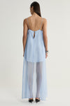 A rear view of a pale blue maxi dress showing its thin shoulder straps, low back and small keyhole opening with a button closure, above a sheer flowing skirt.