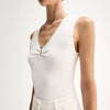 A close-up shows the fitted white sleeveless top with a V-neckline and ruched centre front.