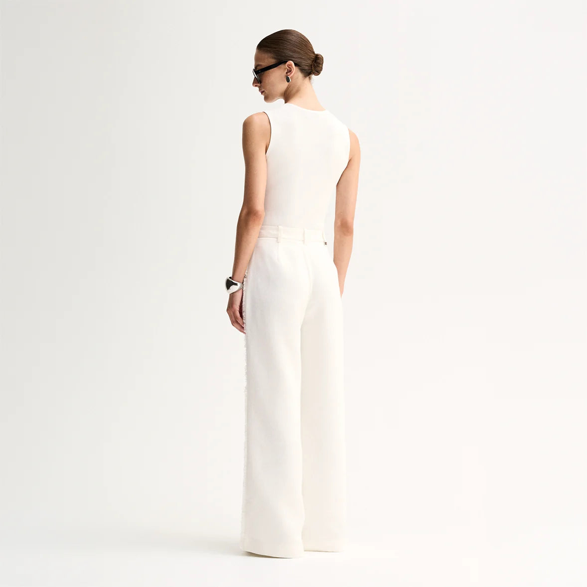 A model wears the Elka Collective Lindsay Knit Top in white with matching wide-leg trousers in a back studio view.
