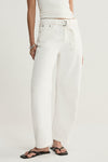 A close-up of ivory denim pants showing the removable fabric tie belt, belt loops, front fastening, metal rivets and curved front pockets.