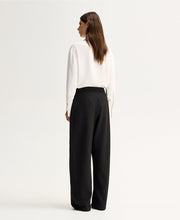 Model wearing the Ivory Elka Collective Millicent Shirt with black wide-leg trousers, showing the clean back and relaxed drape, full-length back view