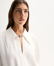 Close-up of the Ivory Elka Collective Millicent Shirt showing the custom silver-tone hardware clasp bridging the deep V-neckline and sharp point collar