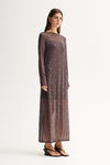 Side view of a woman wearing a slate sheer long-sleeve maxi dress with scattered stud details and a flowing full-length skirt.