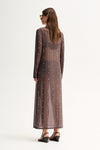 Back three-quarter view of a woman wearing a slate sheer maxi dress with long sleeves and scattered stud detailing.