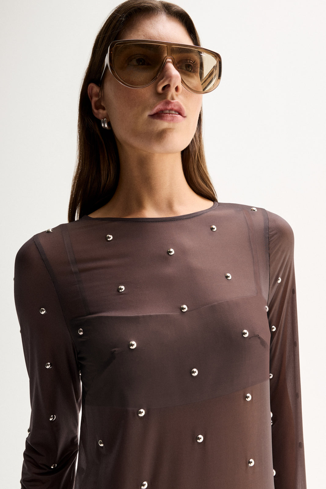 Close-up view showing the slate sheer fabric, crew neckline, long sleeve and scattered hot fix stud details.