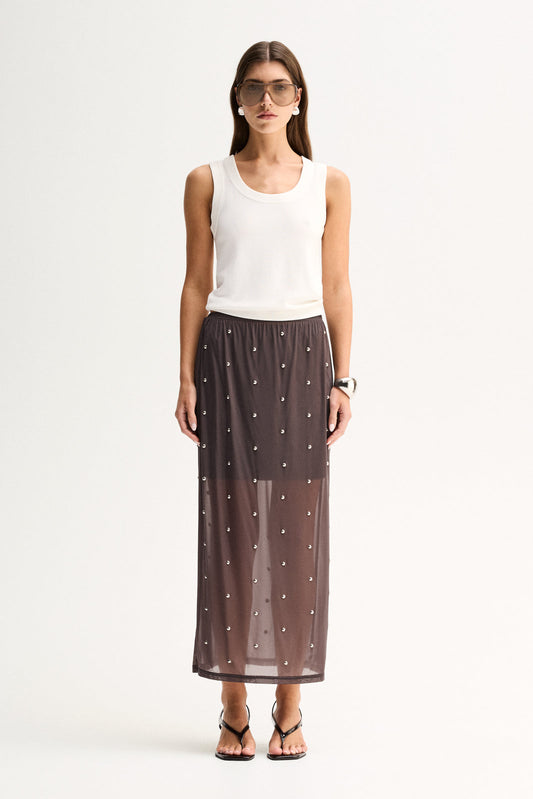 A woman wearing a slate sheer midi skirt with all-over stud details, an elasticated waist and a white sleeveless top in a full-length front view.