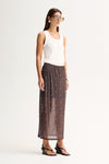 Side view of a woman wearing a slate sheer midi skirt with an elasticated waist, stud detailing and a flowing midi-length hem.