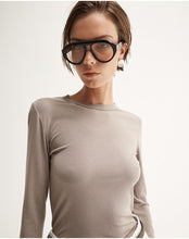 Model wearing the Almond Marle Sierra Top with oversized black sunglasses, showing the slim fit, long sleeves, round neckline and smooth fine-knit finish, close-up front view
