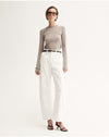 Model wearing the Almond Marle Sierra Top with white trousers and flat sandals, showing the slim silhouette, long sleeves and hip-length fit, full-length front view
