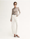 Model wearing the Almond Marle Sierra Top with white trousers, showing the fitted shape, round neckline and streamlined long sleeves, full-length front angled view
