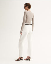 Model wearing the Almond Marle Sierra Top with white trousers and flat sandals, showing the slim fit, long sleeves and clean back silhouette, full-length back angled view