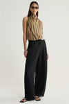A model wears a sleeveless moss, cream and dark striped top with a high gathered neckline, paired with wide-leg black trousers, black sandals, narrow sunglasses and silver earrings in a full-length front three-quarter studio view.