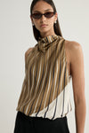 A close-up portrait of a model wearing a moss, cream and dark striped top, highlighting the gathered high neckline, fluid fabric, curved colour-blocked pattern, narrow dark sunglasses and silver earrings.