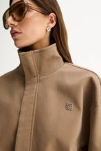 Close-up of the Camel Elka Collective Trixie Jacket showing the stand collar and signature silver-tone Elka Collective monogram hardware