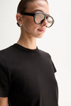 A close-up of a black T-shirt showing the round crew neckline, neatly finished collar seam and short sleeve against the upper chest.