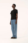 Model wearing the black Zoe Tee with light blue jeans and black sandals, showing the straight hem, relaxed fit and short sleeves, full-length side angled view
