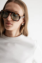 Close-up of model wearing the white Zoe Tee with oversized black sunglasses, showing the classic crew neckline, short sleeves and smooth organic cotton finish, front view
