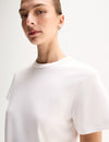 A close-up of a model wearing a white short-sleeve T-shirt, highlighting the crew neckline, relaxed shoulder line and loose sleeve shape.