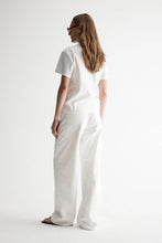 Model wearing the white Zoe Tee with white relaxed trousers, showing the boxy silhouette, short sleeves and clean straight hem, full-length back angled view