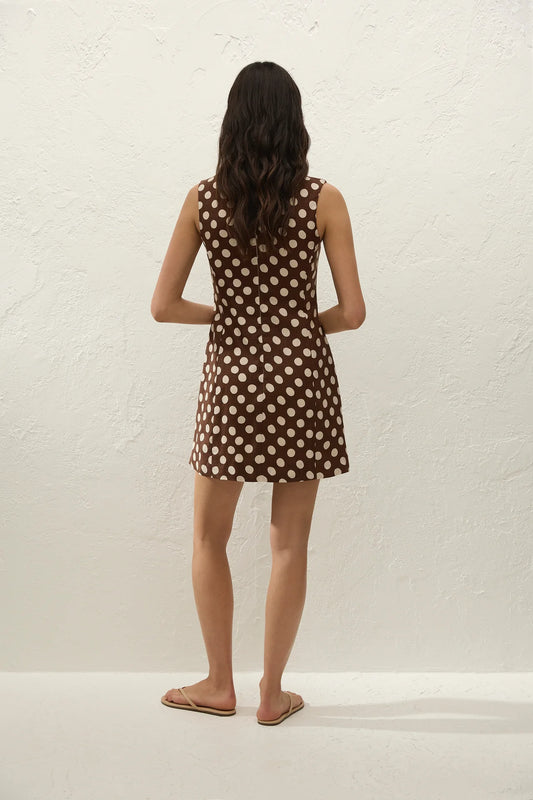Woman wearing a brown polka dot dress against a white background