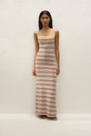 Full-length front view of the striped maxi dress styled with flat sandals against a textured cream wall.