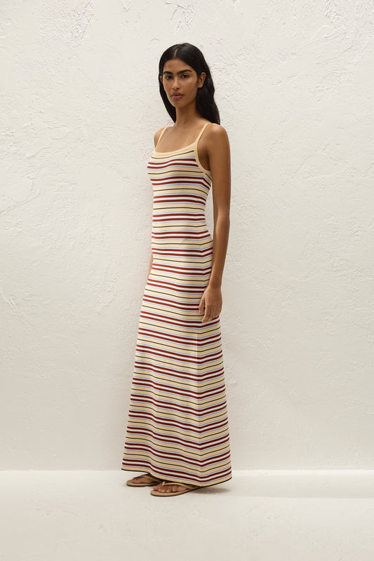 Three-quarter side view showing the fitted silhouette, slim straps and floor-length striped skirt.