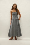 A woman wears a black and white gingham midi skirt with a matching strapless top and black sandals.

