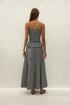 A woman wears the black and white gingham midi skirt in a full-length back view.
