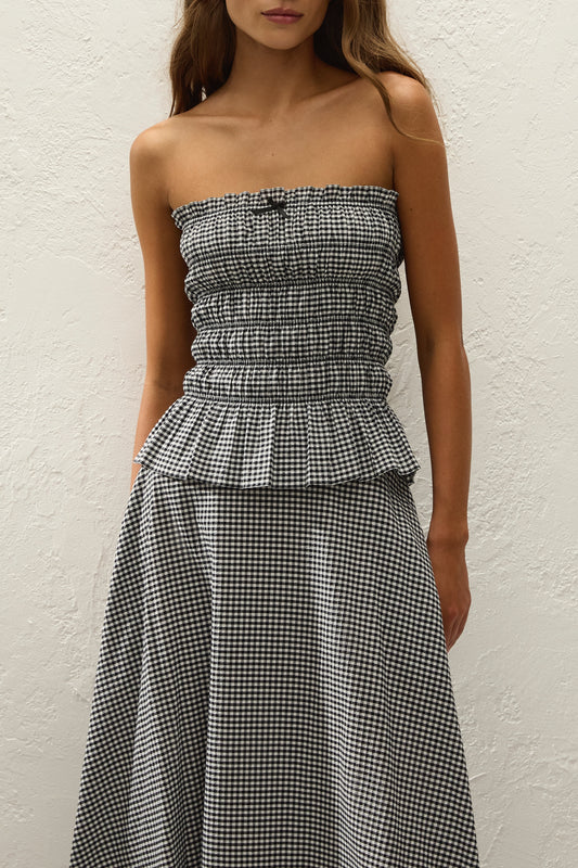 A close-up front view shows the black and white gingham top with a shirred bodice, frilled neckline and peplum hem.
