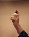 Gentle Habits Ritual Room & Linen Spray in Byron Bay shown in a hand-held front view with its rounded bottle and black spray top.