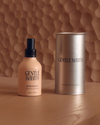 Byron Bay room and linen spray shown beside its cylindrical metal container on a wooden surface.