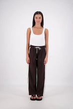 Woman wearing a white tank top and black pants with a white background