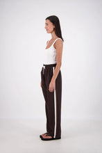Woman wearing a white top and black pants with a white stripe on a white background