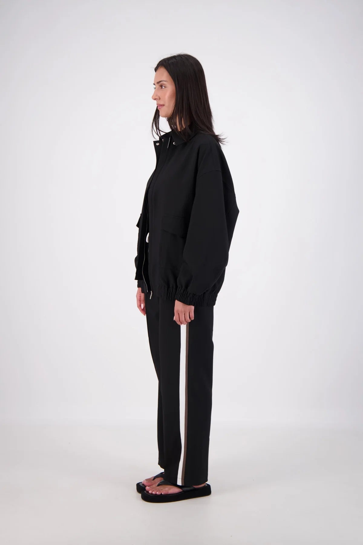 Jasmine Alexa Ischia Bomber Jacket in Black, full-length side view on model.
