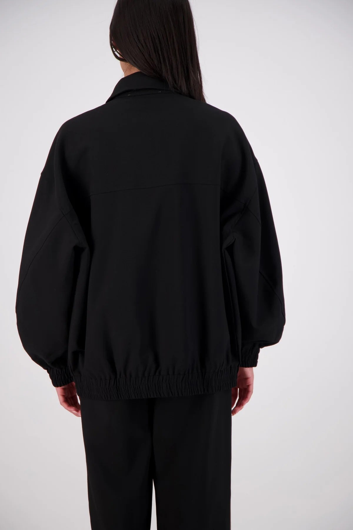Jasmine Alexa Ischia Bomber Jacket in Black, back view showing the oversized silhouette and elasticated hem.