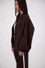 Person wearing a brown jacket and pants on a white background