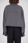 Rear view of a black and white check bomber jacket showing the all-over grid pattern, loose-fitting sleeves, back panel seams and gathered hem.