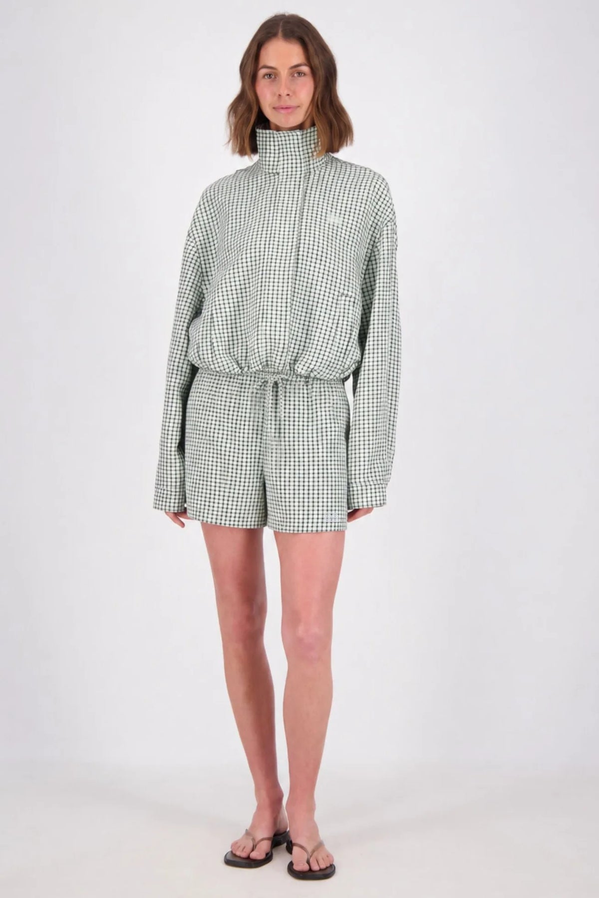 A full-length studio view of the white and mint check bomber jacket paired with matching shorts, showing the high neckline, drawstring hem and coordinated check pattern.