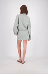 A rear view of the white and mint check bomber jacket, showing the all-over grid pattern, loose long sleeves, back yoke seam and cropped hem.