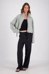 A close front view of the white and mint check bomber jacket, highlighting the high collar, front zip fastening, side pocket opening and small embroidered chest emblem.