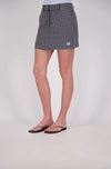 Front three-quarter view of a black and white check mini skort with a structured shape, belt loops, front pockets, a concealed front fastening and a small embroidered double-circle logo near the hem.