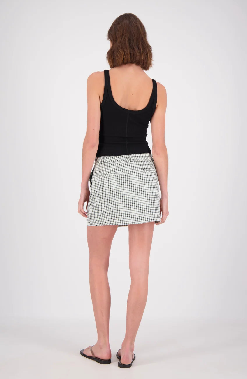 A rear view of a woman wearing a white and mint checked mini skort with a black sleeveless top, showing the back fit and hemline.